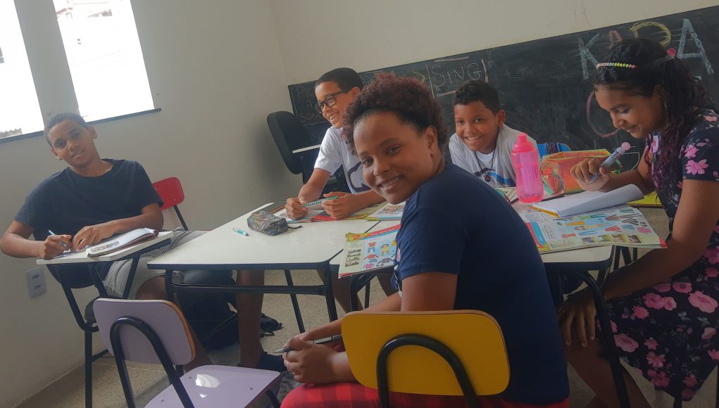 Socialização na adolescência na prática. Grupo de jovens interagindo em sala de aula.