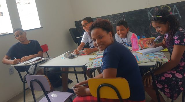 Socialização na adolescência na prática. Grupo de jovens interagindo em sala de aula.