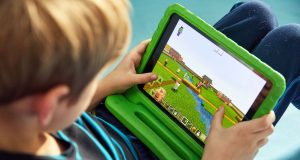 Aprender inglês com videogames: Roblox e Minecraft ajudam? Criança focada e sorridente no joguinho. É possível aprender inglês com videogames no computador.